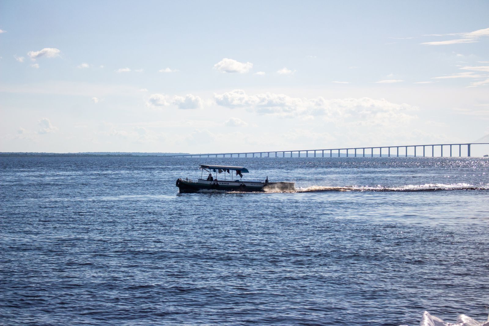 Regional riverboat on the Rio Negro near Manaus with the Rio Negro bridge behind, Amazon river cruise Brazil